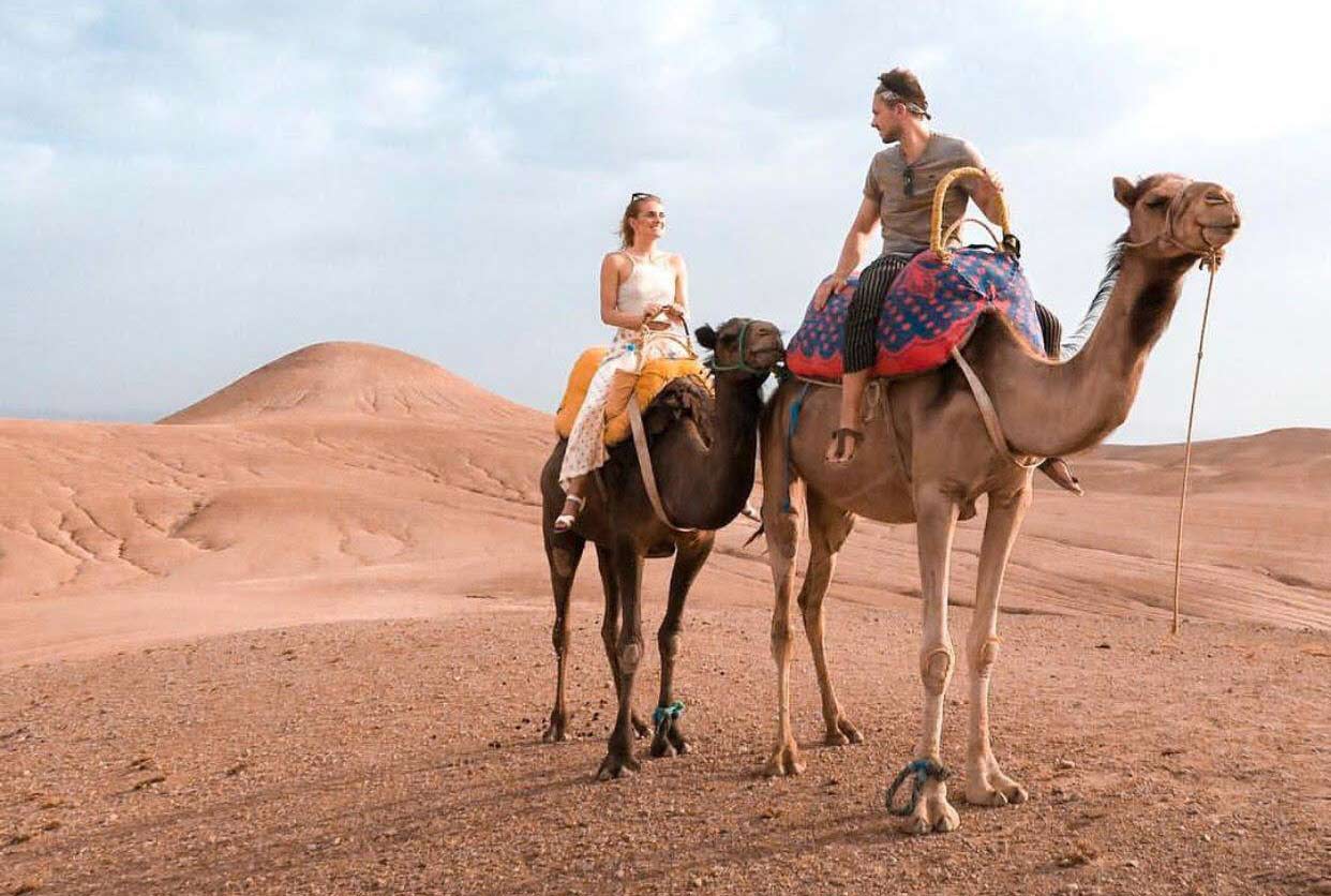 Couple riding camels in the Agafay Desert