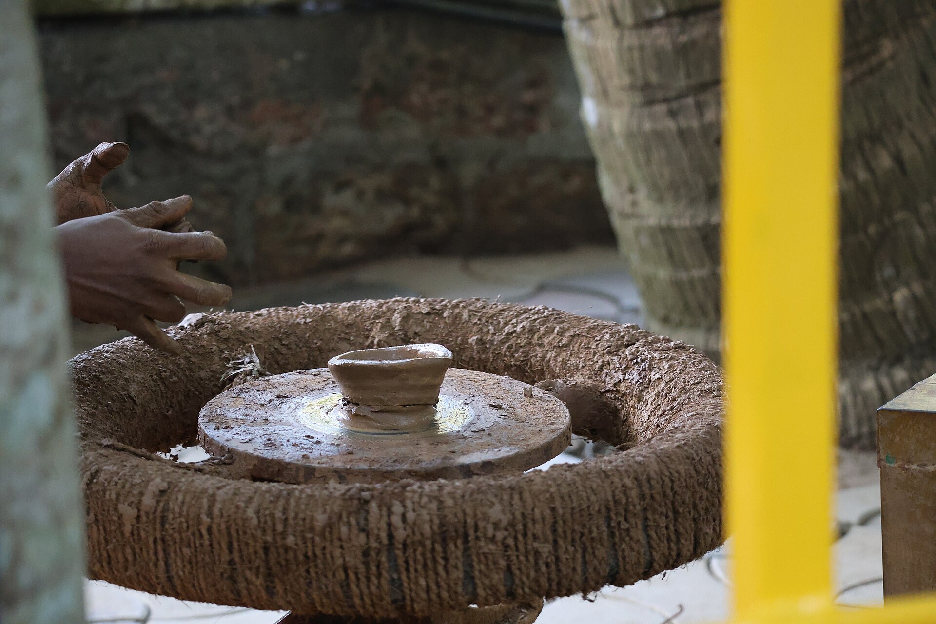 Potter shaping a piece on a traditional manual wheel