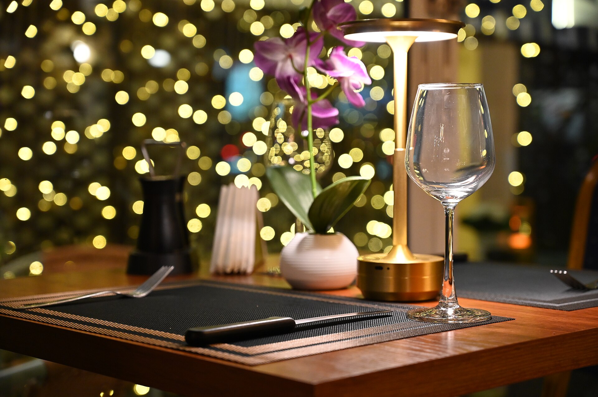 A private candlelit table for two set with soft lighting and a single flower