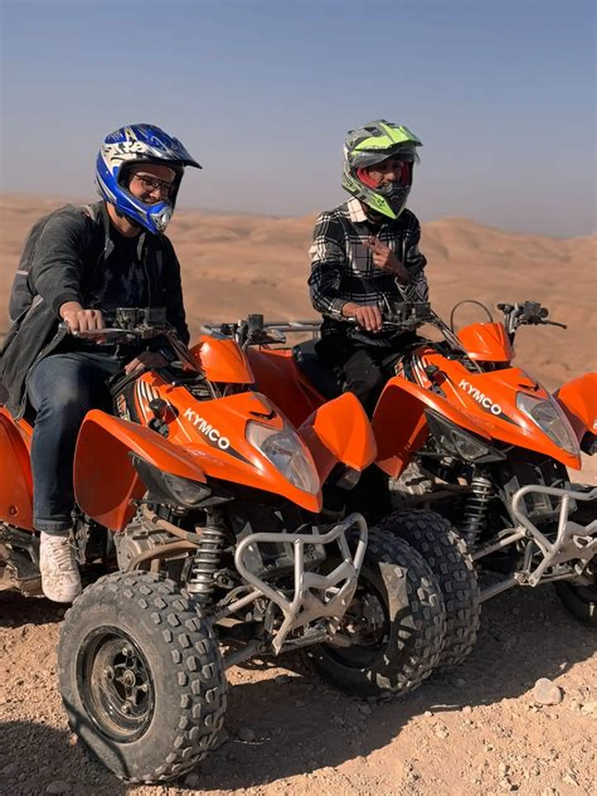 Two riders on orange quad bikes in the desert
